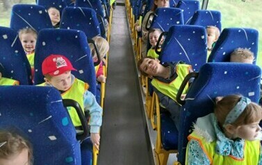 Zdjęcie przedstawia dzieci siedzące w autobusie.