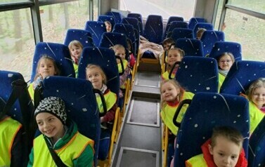 Zdjęcie przedstawia dzieci siedzące w autobusie.